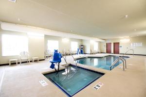 魔鬼湖Cobblestone Hotel & Suites - Devils Lake的医院里的一个大型游泳池,配有桌椅