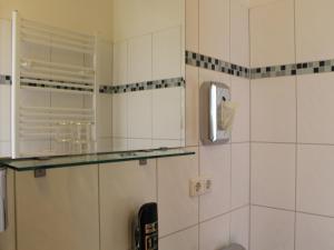 奥芬巴赫艾瑞纳酒店的浴室设有白色瓷砖墙壁和玻璃架子