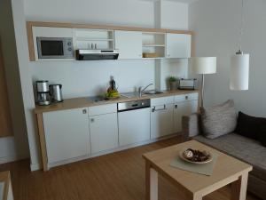 劳特尔巴赫Hotel Goor und Apartmenthaus的客厅里设有白色橱柜和桌子的厨房