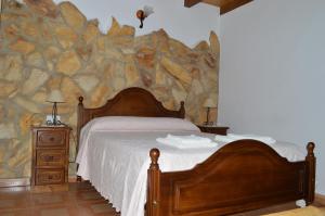 纳瓦孔塞霍Casas Rurales Carrizosa的一间卧室设有一张床和石墙