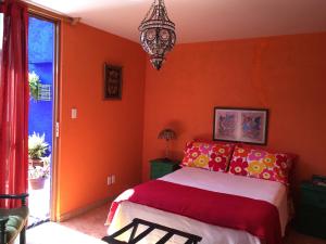 墨西哥城Maria Del Alma House的一间卧室设有橙色的墙壁、一张床和一个吊灯。