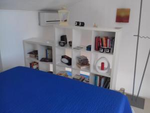 马劳萨Casa dei Fenicotteri的一间卧室设有蓝色的床和书架