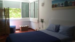 帕雷迪PRAIA DAS AVENCAS Apt junto ao mar com estacionamento e AC的一间卧室设有蓝色的床和窗户。
