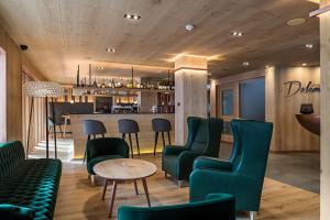 塞尔瓦迪加尔代纳山谷Hotel Garni Dolomieu的一间设有绿色椅子的餐厅和一间酒吧