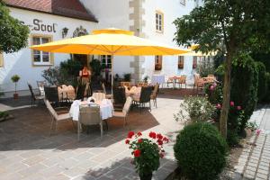 因戈尔施塔特施劳斯沃特酒店的庭院配有桌椅和黄色雨伞。