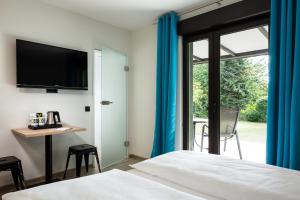 克桑滕Xotel的一间卧室配有一张床、一张书桌和一台电视。