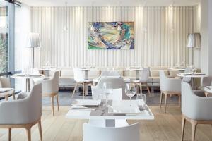 阿格德角卡普德阿格德高尔夫美居酒店的餐厅配有白色的桌椅和墙上的绘画作品