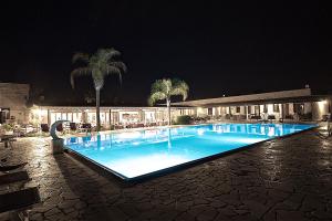 普雷西切Hotel Masseria Le Pajare的棕榈树和建筑的游泳池