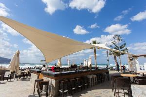 玛利亚Dessole Malia Beach - All Inclusive的海滩上的酒吧配有椅子和遮阳伞