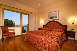陶尔米纳迪奥多罗别墅酒店的卧室配有床、椅子和窗户。
