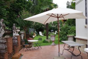 Venegono Superiore普契尼别墅度假屋的庭院配有遮阳伞和桌椅。