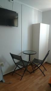 康塞普西翁Hotel con C的配有电视的客房内的一张桌子和两把椅子