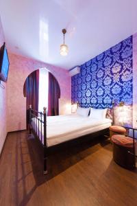 托木斯克卡利弗酒店的一间卧室配有一张蓝色墙壁的床