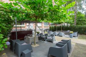 奈梅亨奥拉涅斯塔特酒店的树下带桌椅的庭院
