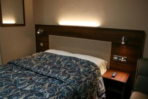 曼彻斯特曼切斯特安居旅馆的一间卧室配有一张床和一个木制床头板