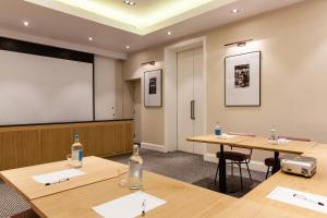 伦敦罗克韦尔设计酒店的一间教室,配有两张桌子和投影屏幕