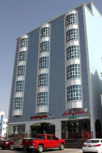 阿尔布亚米Dar Al Khaleej Hotel Apartments的停在大楼前的一辆红色卡车