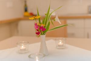 恩斯塔尔豪斯Cafe Pension Kitzer的白色花瓶,桌上放着鲜花和蜡烛