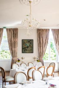 Fourmies马里埃尔城堡酒店的一间配备有白色桌椅和吊灯的餐厅