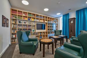 巴特尚道艾博瑞斯登兹温泉酒店的图书馆配有绿色椅子、电视和书架