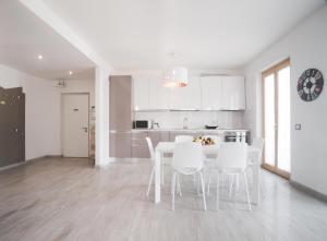 加尔达湖滨Appartamenti Ora e Peler的白色的厨房配有桌子和白色椅子