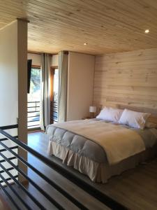 普孔Loft Pucon的一间卧室设有一张带木墙的大床