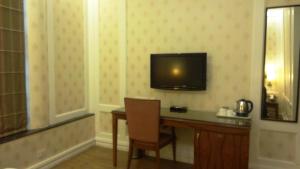 新德里布莱特酒店的酒店客房设有一张桌子和一台墙上的电视