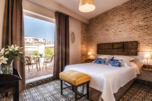 塞维利亚卡萨德科隆精品酒店的一间卧室设有一张床和砖墙