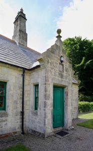 巴利卡斯尔Magherintemple Lodge的一座古老的石头建筑,设有绿门