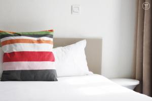 拉罗谢尔亨利四世酒店 的白色的床,上面有红色和白色的枕头