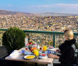 非斯法拉杰宫套房酒店的坐在桌子上,享有城市景观的女人