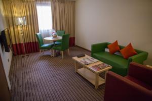 迪拜萨佛伦精品酒店的客厅配有绿色沙发和桌子
