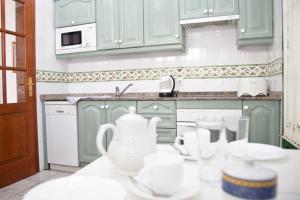 卡门港Villas Bocaina Beach的厨房配有绿色橱柜和台面上的白色菜肴