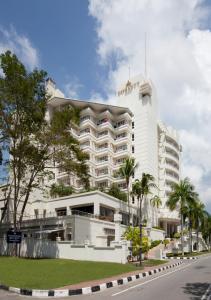 拉布安纳闽帝盛君豪酒店的一座白色的大建筑,前面有棕榈树