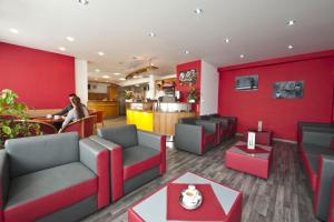 布拉迪斯拉发普乐斯酒店的餐厅设有红色的墙壁、沙发和柜台