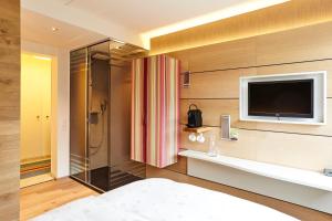 巴塞尔斯坦恩斯坎泽城市酒店的一间带淋浴的浴室和墙上的电视