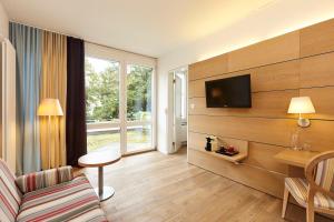 巴塞尔斯坦恩斯坎泽城市酒店的客厅配有沙发和墙上的电视