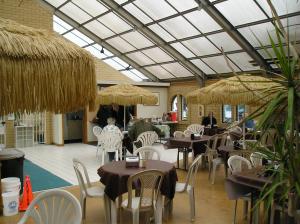 西塞德Seaside Camping Resort Studio Cabin 3的一间带桌椅和稻草伞的餐厅