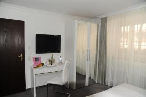 莱茵河畔威尔Hotel Adler - Weil am Rhein的白色的客房设有一张书桌和一台电视机