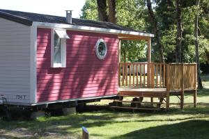奥雷龙圣皮耶尔Camping Fleur d'Oleron的粉红色的小房子,设有木门廊