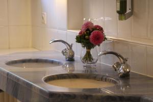 慕尼黑索纳尔霍夫酒店的浴室水槽设有两个水槽和花瓶