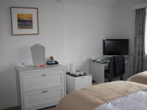 霍伊莱克Seaways Cottage Hoylake的一间卧室配有一张床、一个梳妆台和电视。