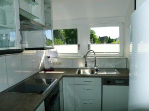 LipperreiheFerienwohnung Schuberski的白色的厨房设有水槽和2扇窗户