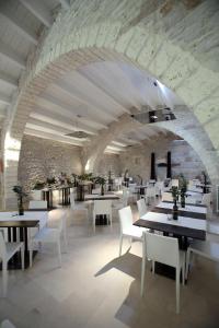 蒙特堡Masseria Torre Di Nebbia的一间设有桌子和白色椅子的餐厅以及石墙