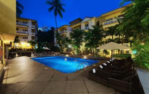 帕纳吉Sandalwood Hotel & Suites的一座游泳池,在晚上在建筑物前