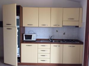 巴德希Casa Vacanze Residence I delfini的厨房配有白色橱柜、水槽和微波炉