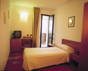 Gazzaniga塞雷内拉酒店的酒店客房配有一张床、一张书桌和一台电视。