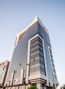 阿布扎比Executive Suites Abu Dhabi的一座高大的玻璃建筑,背后是蓝天