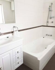 珀斯Kenata-Fairway Apartment Hotel的白色的浴室设有浴缸和水槽。