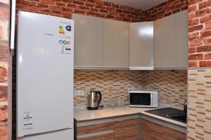 阿拉木图艺术旅舍的厨房配有白色橱柜和砖墙